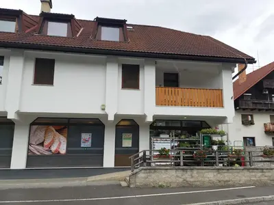 a white building with a store on a street at Apartment Veninsek in Luče