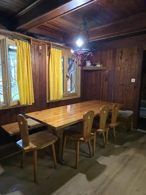 a wooden table and chairs in a room at Koča Pastirica - Velika planina in Stahovica