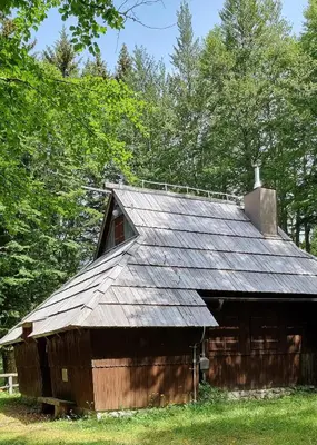 an old wooden barn with a metal roof at Koča Pastirica - Velika planina in Stahovica
