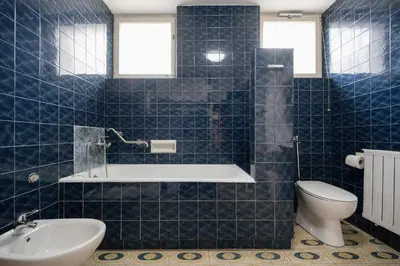 a blue tiled bathroom with a tub and a toilet at Ljubljana C17 4-Bedroom Private Row House with Garden and Parking in Ljubljana