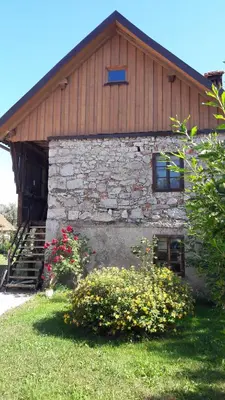 a stone building with flowers in front of it at Apartma Sterle in Stari Trg pri Ložu
