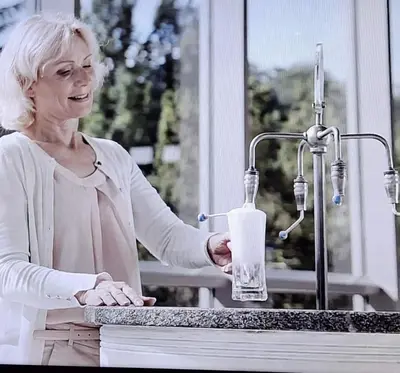 a woman standing at a counter holding a glass at VILLA GOLF Crystal Drop Apartment in Rogaška Slatina
