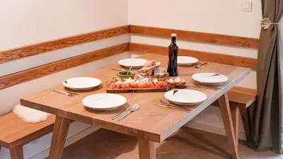 a wooden table with plates and a bottle of wine at Zidanica Muhič in Dolenjske Toplice