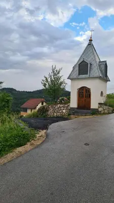 a church with a cross on top of a road at Zidanica Muhič in Dolenjske Toplice