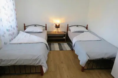 three beds in a room with a lamp on a table at Martinka apartments in Jelšane