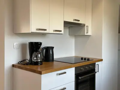 a kitchen with white cabinets and a black stove at ANMARI Apartment & Rooms in Radovljica