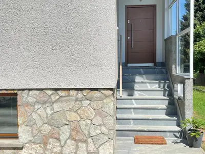 a house with a stone wall and a door at ANMARI Apartment & Rooms in Radovljica