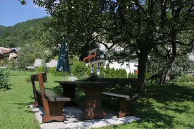 a picnic table and a bench under a tree at Apartments & Rooms Stare in Bohinj