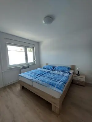a bedroom with a bed with a blue comforter and a window at Apartments Marica in Kranjska Gora