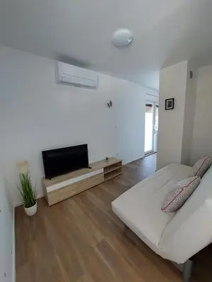 a white living room with a couch and a flat screen tv at Apartments Marica in Kranjska Gora