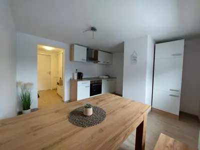 a living room with a wooden table and a kitchen at Apartments Marica in Kranjska Gora