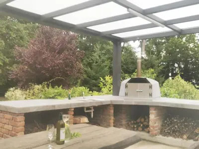a patio with an outdoor kitchen with a grill at Holiday Home - Goričko Park in Kobilje