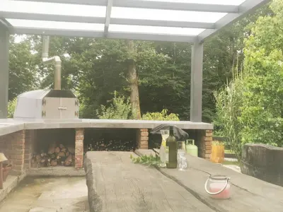 a outdoor kitchen with a stove and a table at Holiday Home - Goričko Park in Kobilje