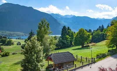 a cabin in a field with mountains in the background at Veduta Apartment Bohinj Lake in Bohinj