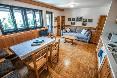 a kitchen and living room with a table and a couch at Veduta Apartment Bohinj Lake in Bohinj