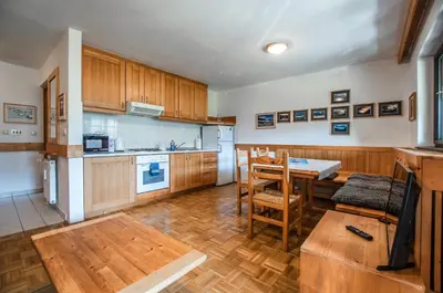 a kitchen with wooden cabinets and a table and chairs at Veduta Apartment Bohinj Lake in Bohinj
