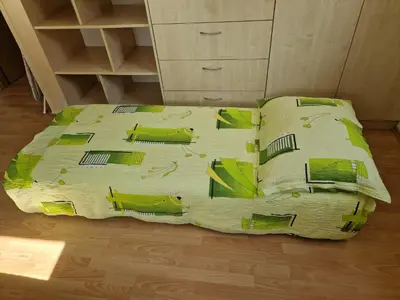 a bed with a green comforter and pillows on it at Apartment Amak with free onsite parking in Bovec