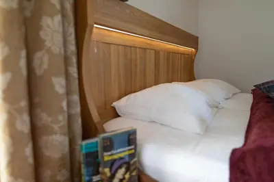 a bed with a wooden headboard and white pillows at Apartments Vila Jelka in Bohinj