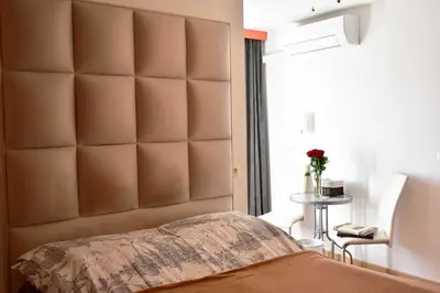 a bedroom with a large padded headboard and a table at Sobe - Rooms Stremljan Ljubljana in Medvode