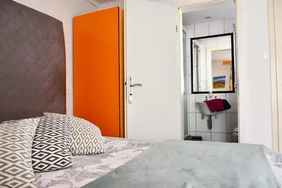 a bedroom with a bed and an orange door at Sobe - Rooms Stremljan Ljubljana in Medvode