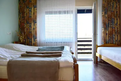 a bedroom with two beds and a large window at Sobe - Rooms Stremljan Ljubljana in Medvode