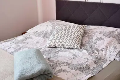 a bed with a blanket and two pillows on it at Sobe - Rooms Stremljan Ljubljana in Medvode