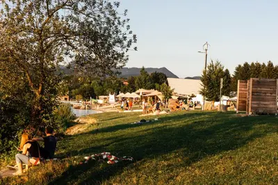 two people sitting in the grass near a body of water at Camp Velenje in Velenje