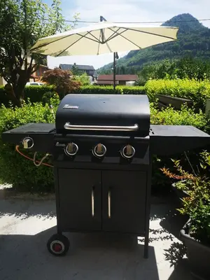 a charcoal grill with an umbrella in a yard at Kiara Apartments & Rooms in Jesenice