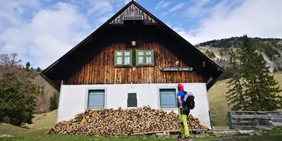 a person standing in front of a building with a pile of wood at Kiara Apartments & Rooms in Jesenice
