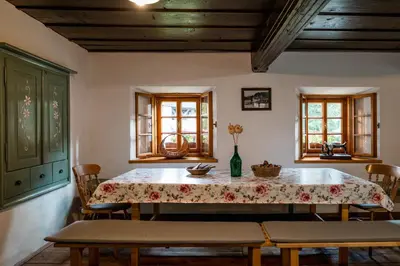 a dining room with a table and chairs and windows at Domačija Gačnik in Idrija