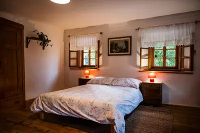 a bedroom with a bed and two windows and two lamps at Domačija Gačnik in Idrija