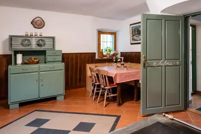 a kitchen with green cabinets and a dining table at Domačija Gačnik in Idrija