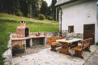 a patio with two benches and a brick fireplace at Domačija Gačnik in Idrija