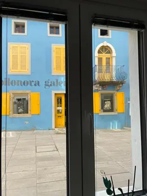 a window view of a blue building with yellow doors at RITUAL in Ajdovščina