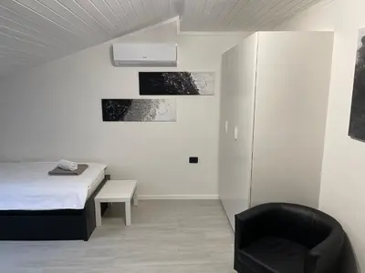 a bedroom with a bed and a black chair at Room Aria in Kobarid