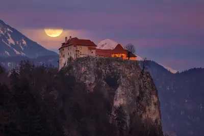 a castle on top of a mountain at sunset at Holiday House Radovna Bled in Zgornje Gorje