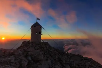 a lighthouse on top of a mountain at sunset at Holiday House Radovna Bled in Zgornje Gorje