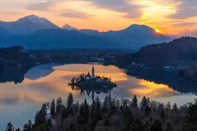 an island in the middle of a lake at sunset at Holiday House Radovna Bled in Zgornje Gorje