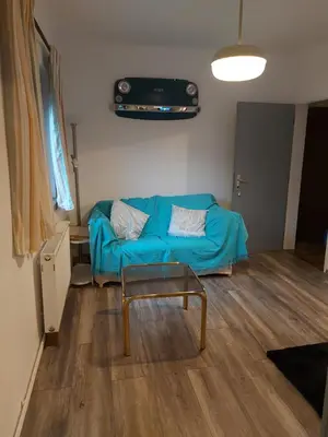 a living room with a blue couch and a table at Pr' Šovarjo in Zgornje Gorje