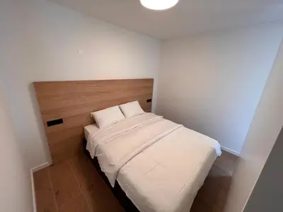 a small bedroom with a white bed with a wooden headboard at Vila Petra - Family apartment for 4 at Lake Bled in Bled