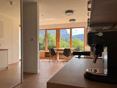 a kitchen with a large window and a dining room with chairs at Vila Petra - Family apartment for 4 at Lake Bled in Bled
