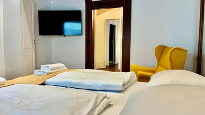 a room with two beds and a tv and a yellow chair at Ars Longa apartments in Ljubljana