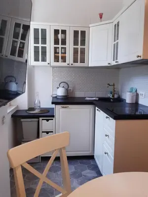 a kitchen with white cabinets and a chair in it at Ars Longa apartments in Ljubljana