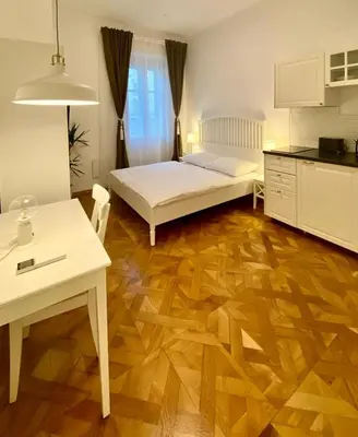 a bedroom with a bed and a table and a kitchen at Ars Longa apartments in Ljubljana