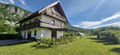 a house in the mountains with a green yard at Apartmaji ob Savi in Bohinj