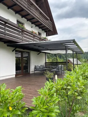 a patio with awning and furniture on a house at Apartmaji ob Savi in Bohinj