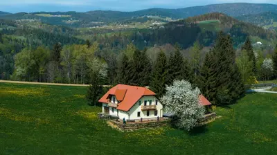 a house with an orange roof on a green field at Frešer Farm Accommodation in Zgornje Prebukovje