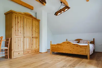 a bedroom with a wooden bed and a wooden cabinet at Frešer Farm Accommodation in Zgornje Prebukovje