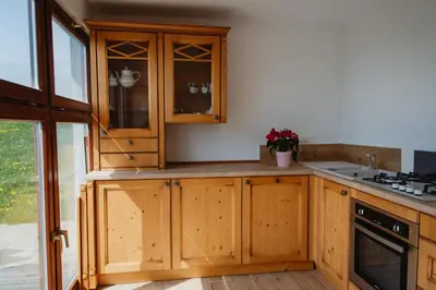a kitchen with wooden cabinets and a sink at Frešer Farm Accommodation in Zgornje Prebukovje