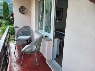 a balcony with two chairs and a table and a window at Sava river house - apartments in Bled